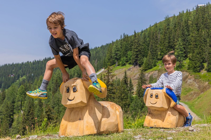 Kinder auf Holzfiguren in der Hopsiland Erlebniswelt auf der Planai in Schladming &copy; Schladming-Dachstein.at / Ren&eacute; Eduard Perhab